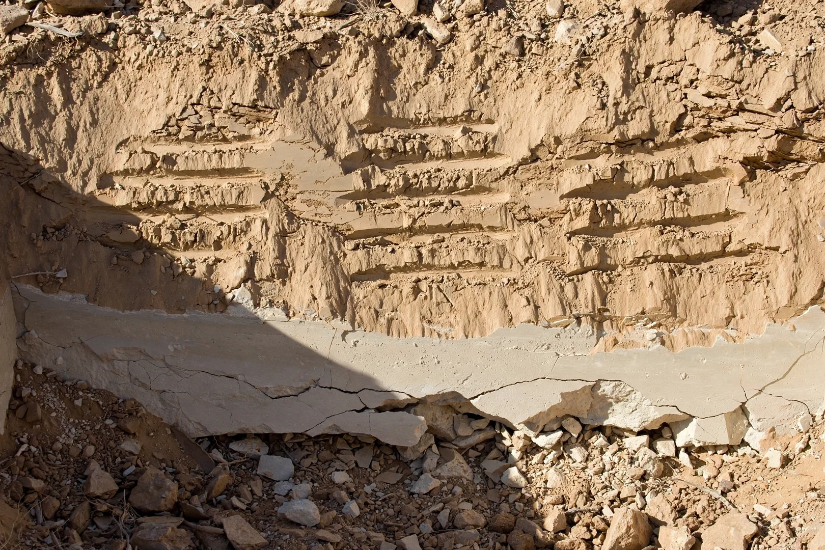 Caliche layer exposed during cut work on a rocky desert lot